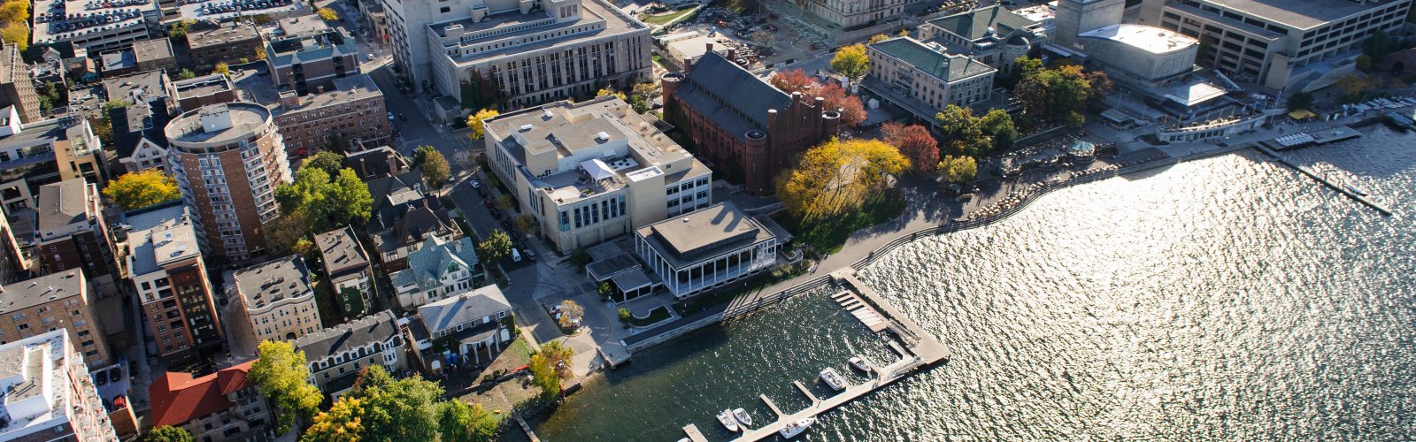 The Lake Mendota shoreline is pictured in an aerial view of the University of Wisconsin-Madison campus during autumn on Oct. 12, 2013. Clockwise from bottom center, major campus facilities include the Goodspeed Family Pier, Below Alumni Center, Pyle Center, Memorial Library, Mosse Humanities Building, construction of the East Campus Mall, Wisconsin State Historical Society, Science Hall, Helen C. White Hall, Memorial Union Terrace and Red Gym (Armory and Gymnasium). The photograph was made from a helicopter looking south. (Photo by Jeff Miller/UW-Madison)