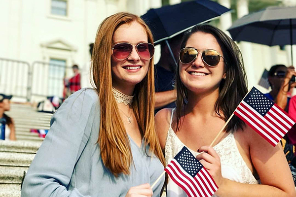 Two women in sunglasses holding American flags
