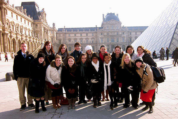 Group of students posing in front of the Louvre museum.