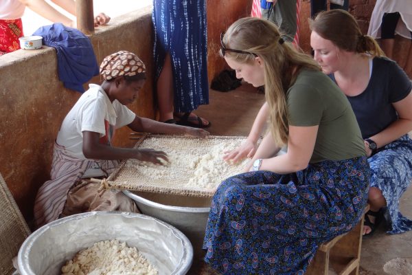 Student processes grain with a Ghanian community member.