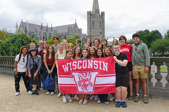 Students pose in front of St. Patrick's Cathedral holding UW flag